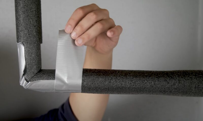 Applying reflective tape to a section of insulated pipe
