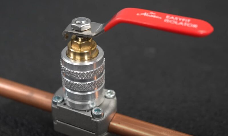 Close-up of a ball valve, featuring a red lever and a textured aluminum body