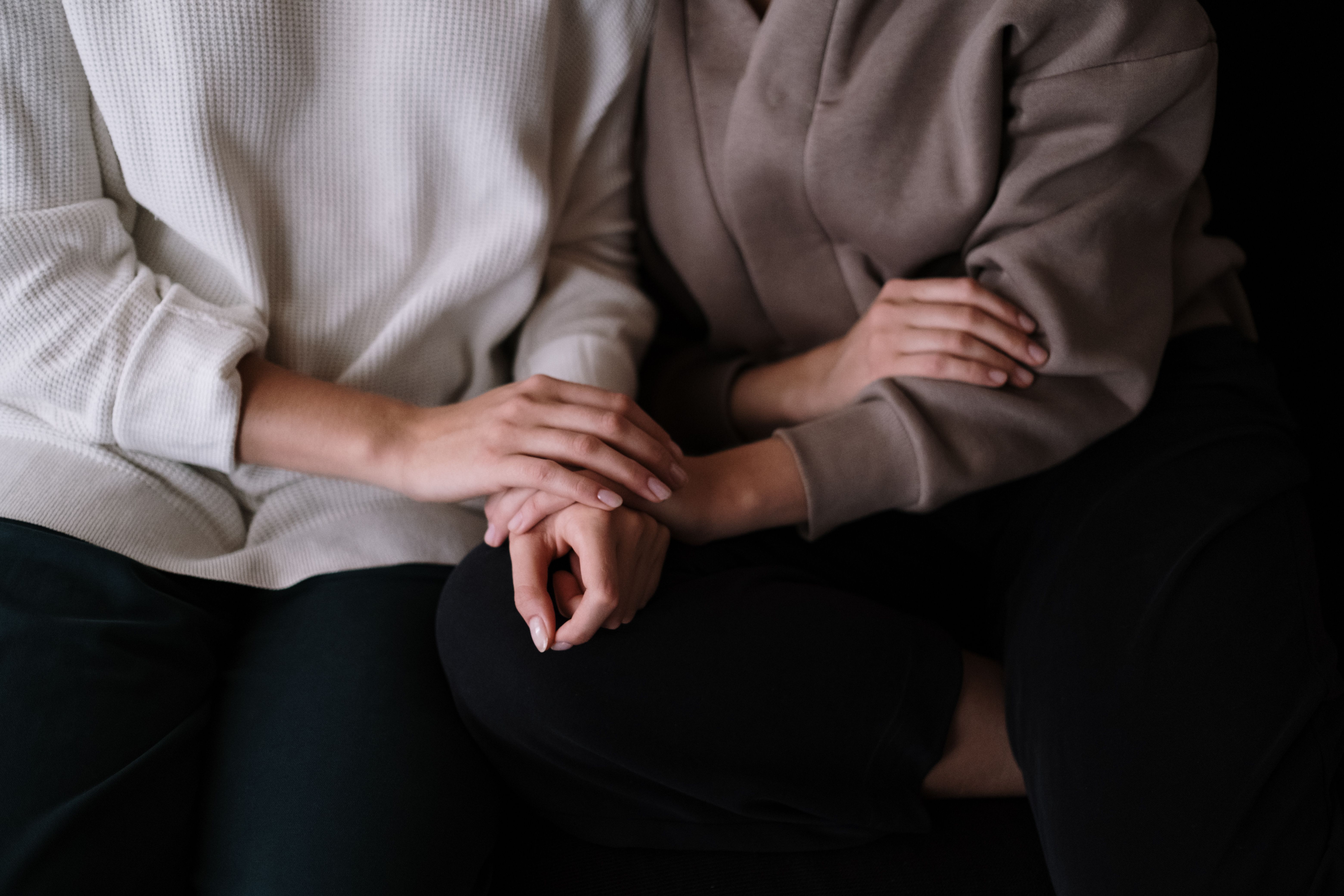 Two people sitting together with a gentle supportive touch, representing human companionship