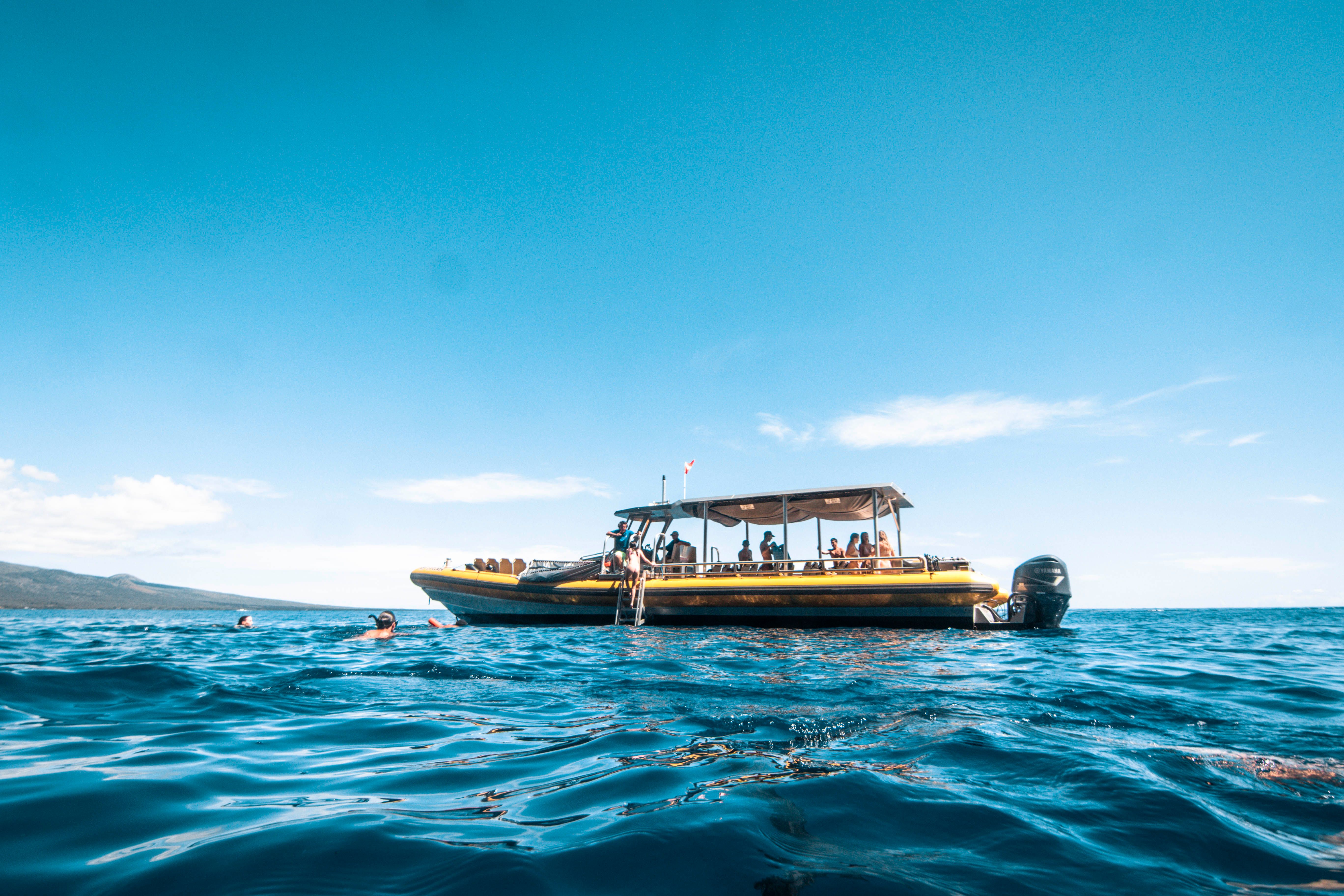 Guests aboard a small motorboat enjoy an ocean outing in Hawaii, suggesting the more intimate feel of a private charter.