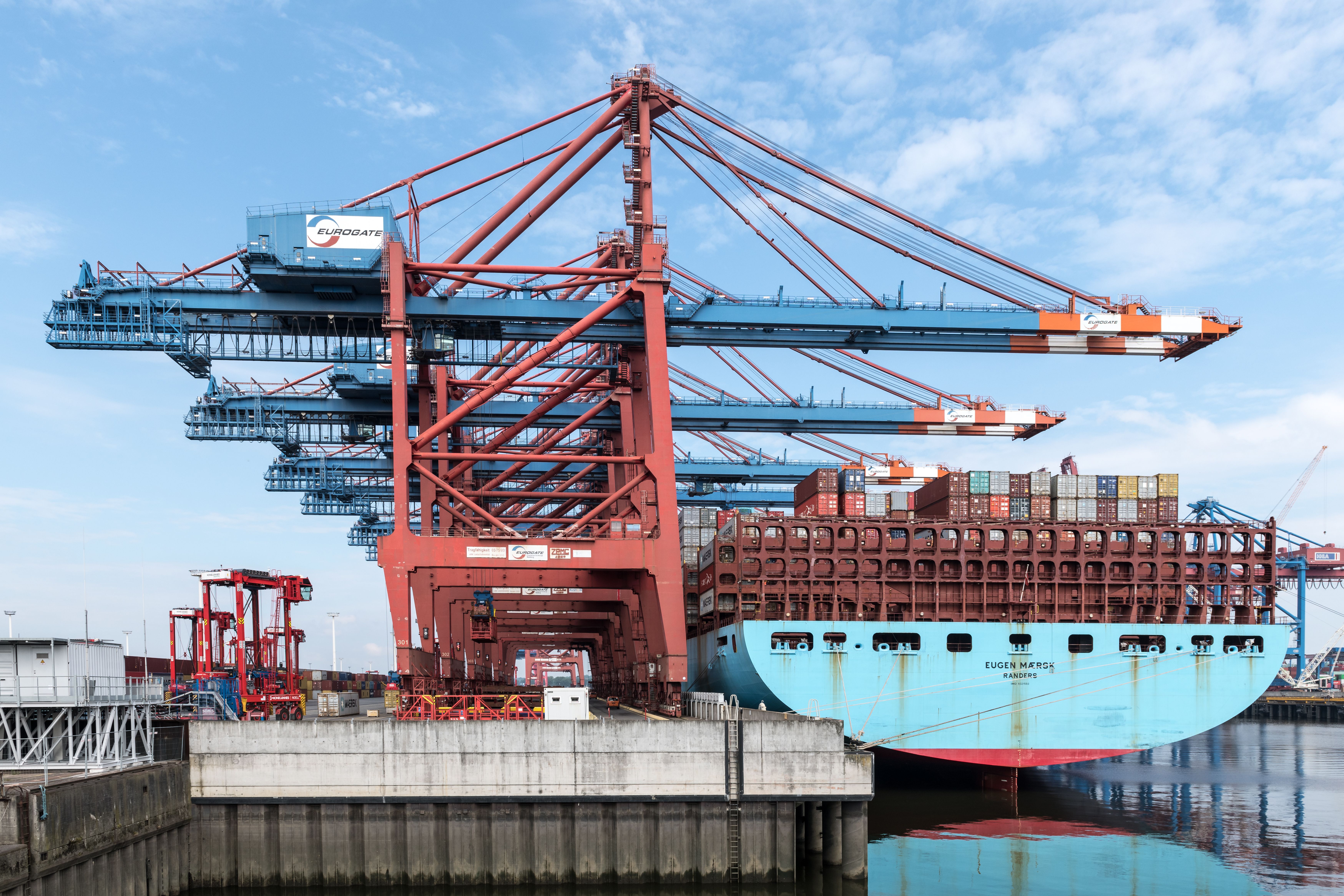 Cargo ship docked at a container terminal with cranes loading freight