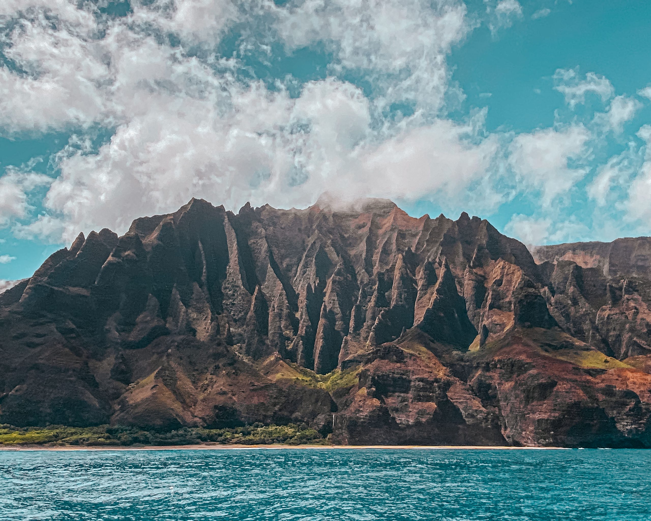 Rugged Na Pali Coast cliffs meet the Pacific, a dramatic backdrop for a Kauai boat charter.